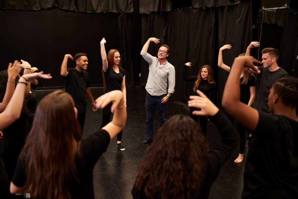 Teacher with drama students in performing arts class