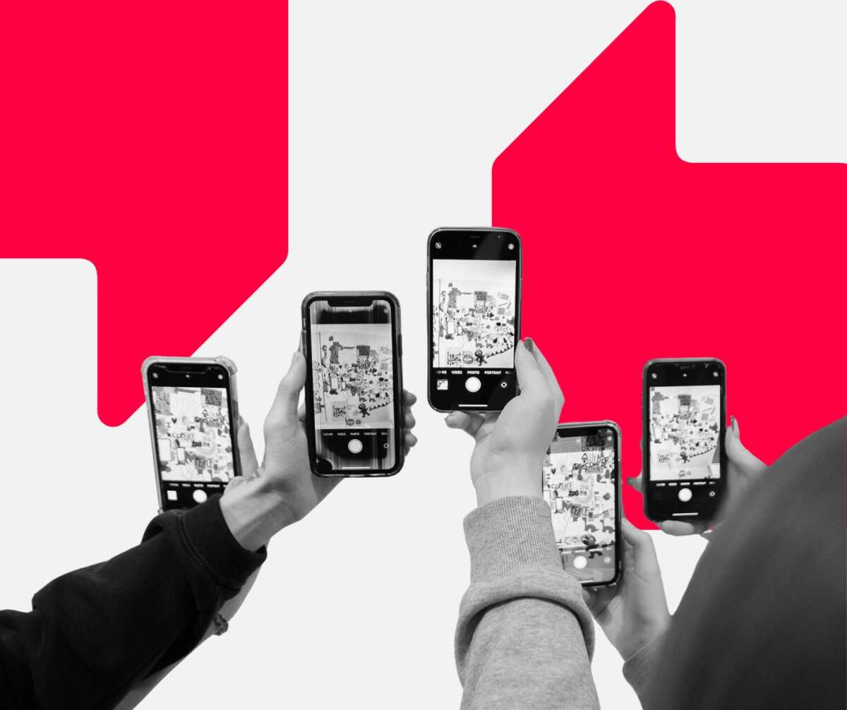 A group of young people hold up mobile phones towards artwork