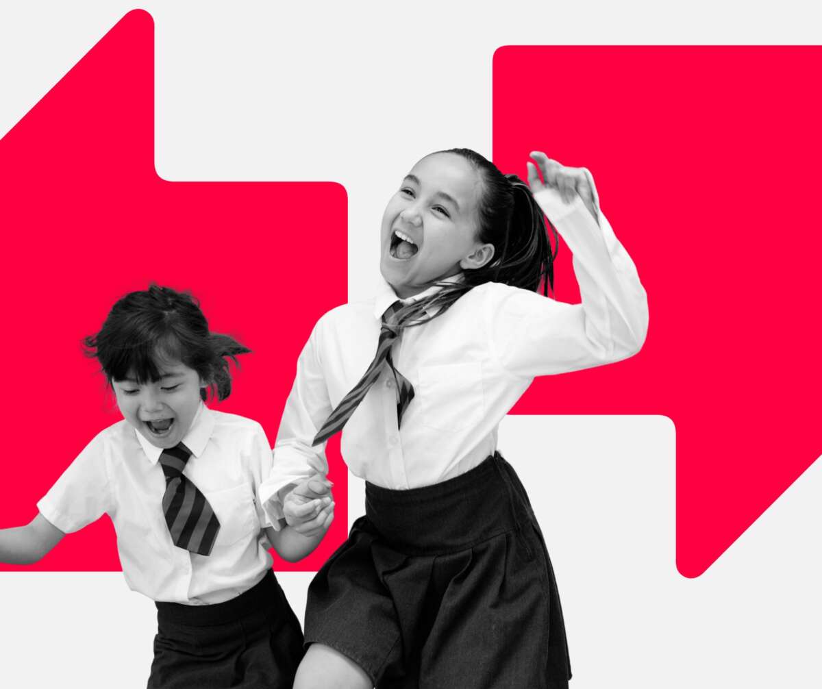 Two young girls in school uniform celebrating